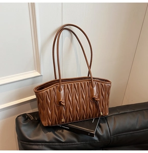 Vue détaillée du sac cabas plissé marron avec détails de nœuds sur fond de cuir noir