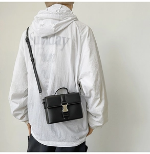Detail of black PU leather crossbody bag with silver buckle and top handle for women