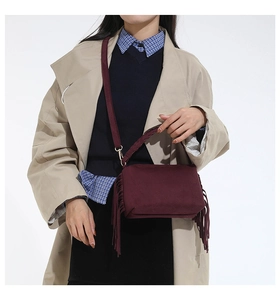 Detail of burgundy fringe crossbody bag with woven handle and matte frosted texture