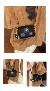 Detail of black woven shoulder bag with wavy edge flap and cute donut charm accessory