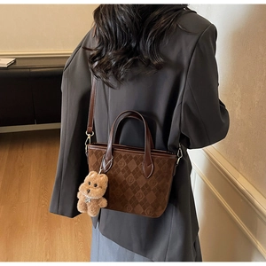 Deep brown suede bucket bag with monogram pattern shown on model in cozy home setting