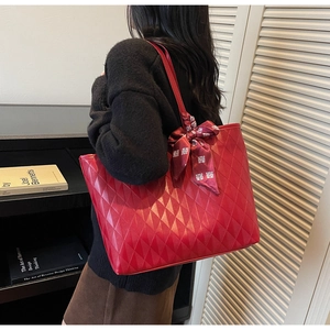 Detalle del bolso tote rojo acolchado con cinta de seda y adorno festivo tradicional