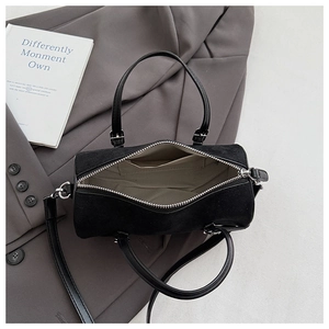 Detail view of black cylinder bag showing herringbone fabric lining and silver zipper