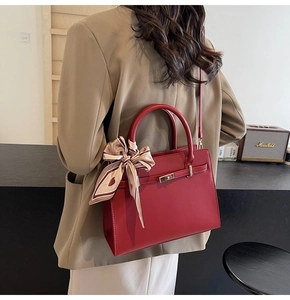 Détail du sac à main rouge en similicuir avec fermoir doré et foulard en soie à coeurs