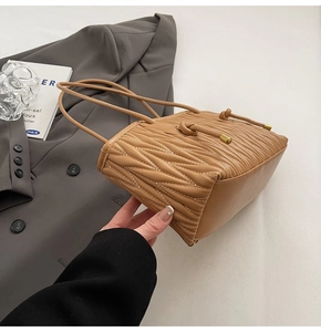 Détail de la texture en cuir PU plissé et de la fine bandoulière cylindrique marron