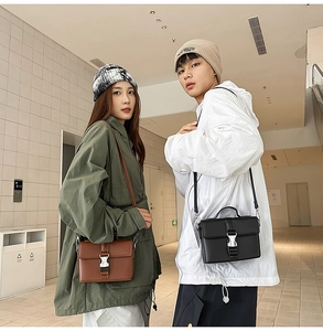 Detail view of brown and black structured PU leather crossbody bags with silver metal buckles