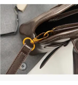 Macro detail of high-quality gold hardware and precise stitching on dark brown leather bag