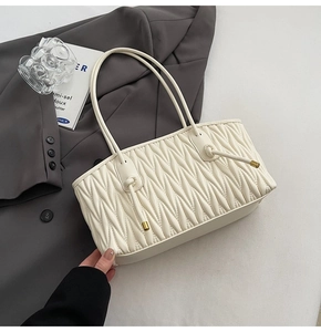 Gros plan sur la texture du cuir plissé blanc crème et les cordons à bouts dorés