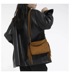 Detail of brown suede shoulder bag with long fringes and handcrafted woven stitching