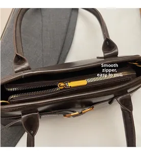 Detail showing smooth gold metal zipper and stitching on a dark brown leather tote bag