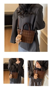 Close-up of brown quilted faux suede bucket bag with logo embossing and plush bear charm