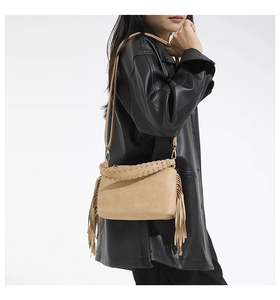 Close-up of camel suede tote bag featuring fringe tassels and woven leather strap details