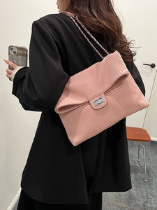 Pink pleated chain shoulder bag for women worn by a model in a black blazer suit