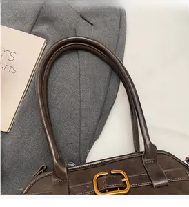 Detail of dark brown tote bag featuring retro gold buckles and sturdy rounded handles
