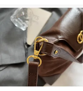Close-up of retro dark brown leather bag showing premium gold metal hardware and hook details