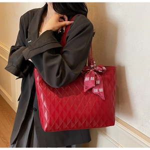 Detalle de bolso tote acolchado rojo con un pañuelo de seda decorativo y caracteres blancos