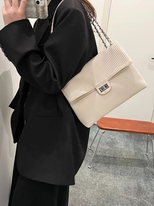 Minimalist cream corduroy chain crossbody bag with silver buckle worn by a model