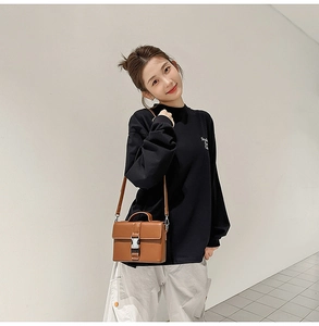 Detail view of a brown PU leather square crossbody bag paired with a casual black sweatshirt