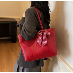 Detalle del bolso tote rojo grande con textura ondulada y adorno de lazo de seda