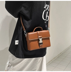 Detail of a brown PU leather crossbody bag featuring a classic silver metal buckle closure