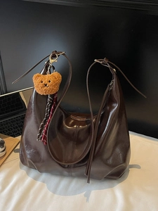 Deep brown glossy underarm bag with a cute bear pendant and woven tassels in retro style
