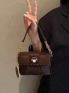 Deep brown square shoulder bag with wavy flap, gold chain strap and donut charm detail