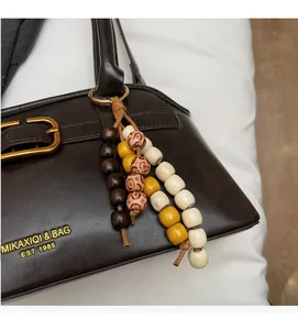 Detail of dark brown leather handbag with vintage gold buckle and bohemian beaded charm