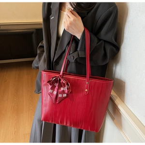 Detalle del bolso tote rojo con textura de ondas y nudo de pañuelo de seda tradicional