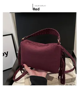 Macro detail of red suede shoulder bag with fringe trim and braided leather handle