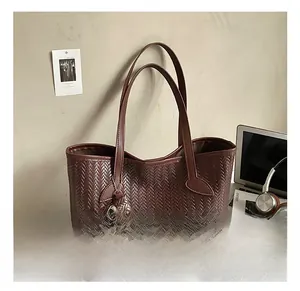 Détail du sac cabas tressé marron foncé avec pochette zippée assortie sur fond lifestyle
