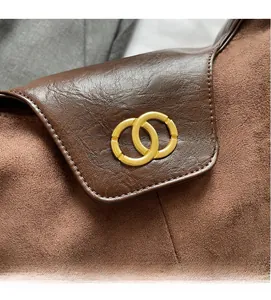 Detail of suede and lychee pattern leather contrast with golden interlocking rings buckle