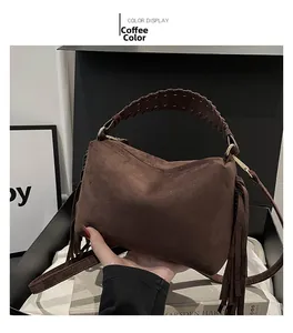 Detail of coffee brown suede tote bag featuring long side tassels and woven handle