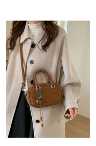 Brown leather retro oval handbag featuring a slim shoulder strap shown in a lifestyle setting