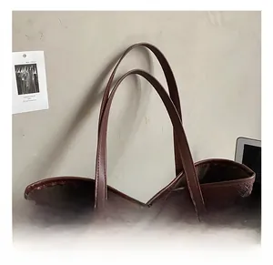 Détail de la texture tressée et des poignées en cuir sur un grand sac cabas marron