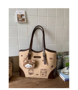 Dettaglio della borsa tote vintage con stampe di gatti, fiocchi e ciondolo orsetto