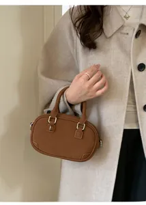 Detail of a brown matte leather mini handbag with silver hardware and fine stitching