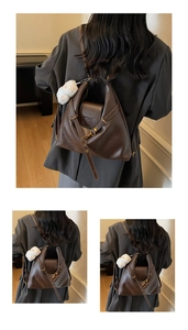 Detail view of dark brown faux leather tote bag with asymmetric cut and plush bear charm