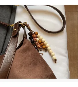Detail of suede leather tote with decorative wooden beads and tassel charms