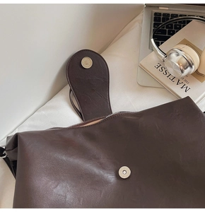 Detailed view of dark brown PU leather tote with magnetic buckle and interior lining