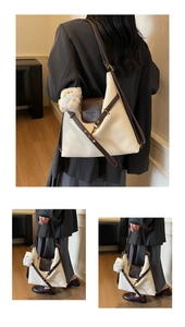 Detail of minimalist beige leather shoulder bag with brown flap and plush bear charm