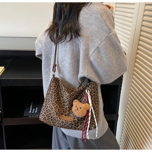 Vue détaillée du sac hobo léopard avec breloque ours sur un tricot gris décontracté