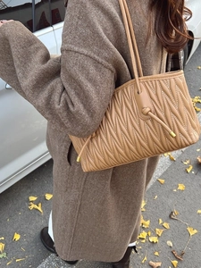 Sac fourre-tout matelassé beige avec plis en V dans un style urbain chic en plein air