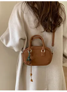 Caramel brown bowling bag in premium textured leather worn with a beige wool coat