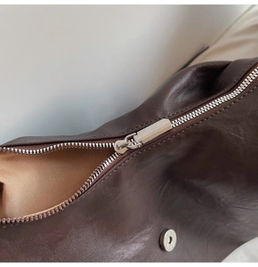Detail of premium smooth silver zipper and dark brown leather texture on a retro tote bag