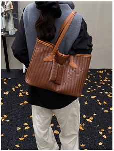Détail d'un grand sac cabas tressé en cuir avec une petite pochette zippée assortie