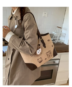 Dettaglio della borsa tote beige con disegno di gatto e ciondolo a testa di gatto in peluche