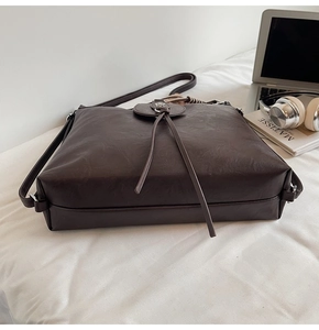 Detail of dark brown leather tote bag with round ring and stylish fringe tassels