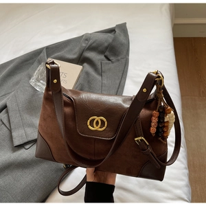 Detail of vintage brown tote bag with suede paneling, golden buckle and bead pendant