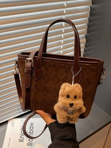 Dark brown suede bucket bag with checkerboard pattern and plush dog charm detail
