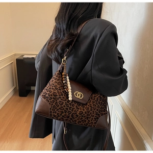 Close-up of leopard print tote bag featuring a golden double-ring buckle and beaded charm